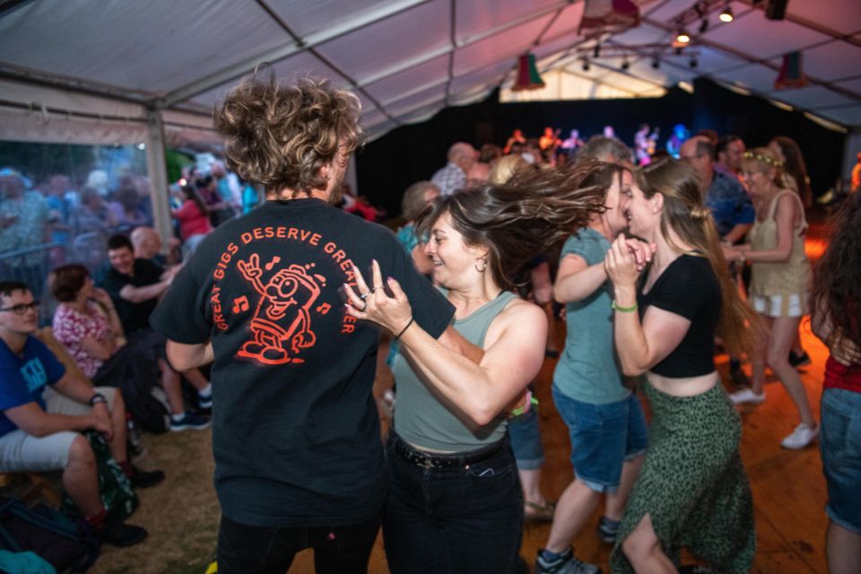 A group of people dance excitedly in a large tent