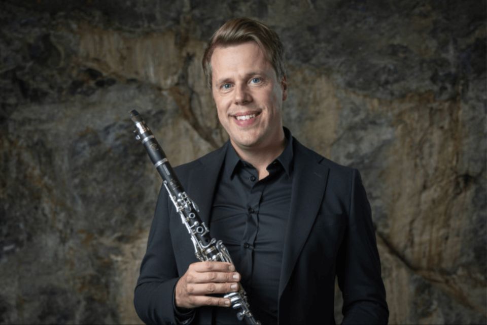 Andreas Sunden wears a black shirt and holds his clarinet, smiling