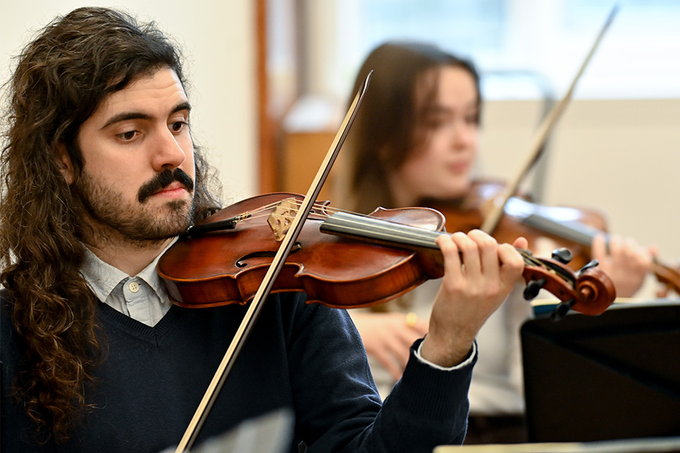 A young man plays the violin with a baroque bow