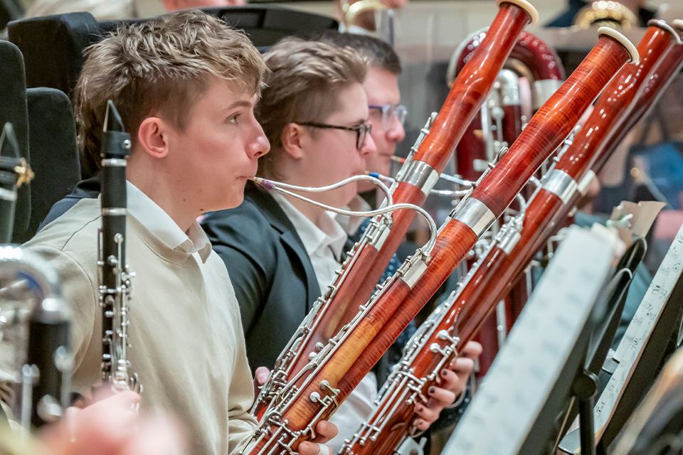 Three bassonists perform on stage as part of a wind ensemble