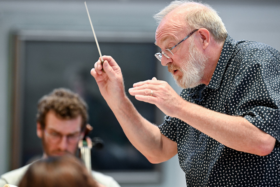 Martyn Brabbins conducts an orchestra on stage