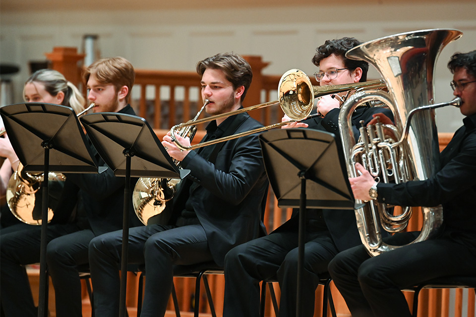 Brass players wearing black perform on stage