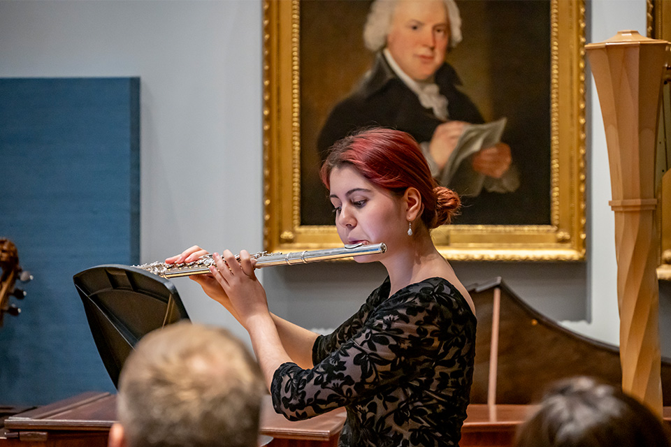 A woman performs a solo flute piece in the RCM Museum