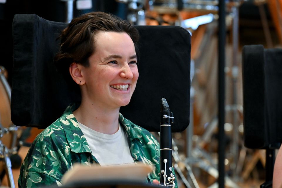 A young woman holding a clarinet laughs
