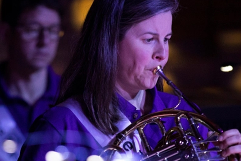 A close up image of Elspeth Dutch playing the horn as part of an ensemble