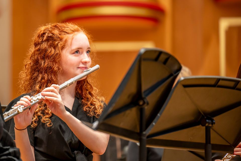 A flautist smiles holding her flute on stage