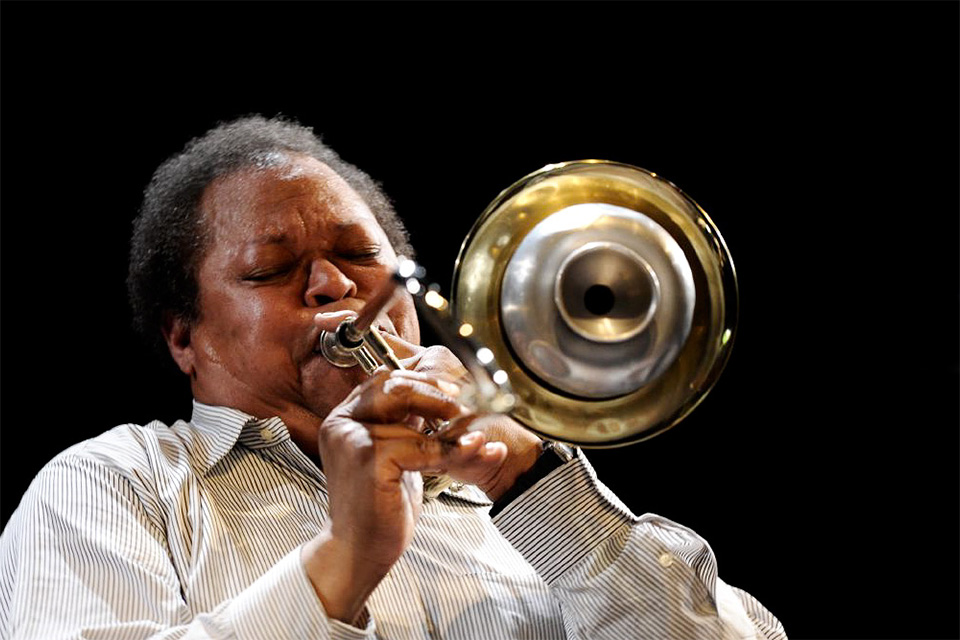 George Lewis plays the trumpet against a dark backdrop