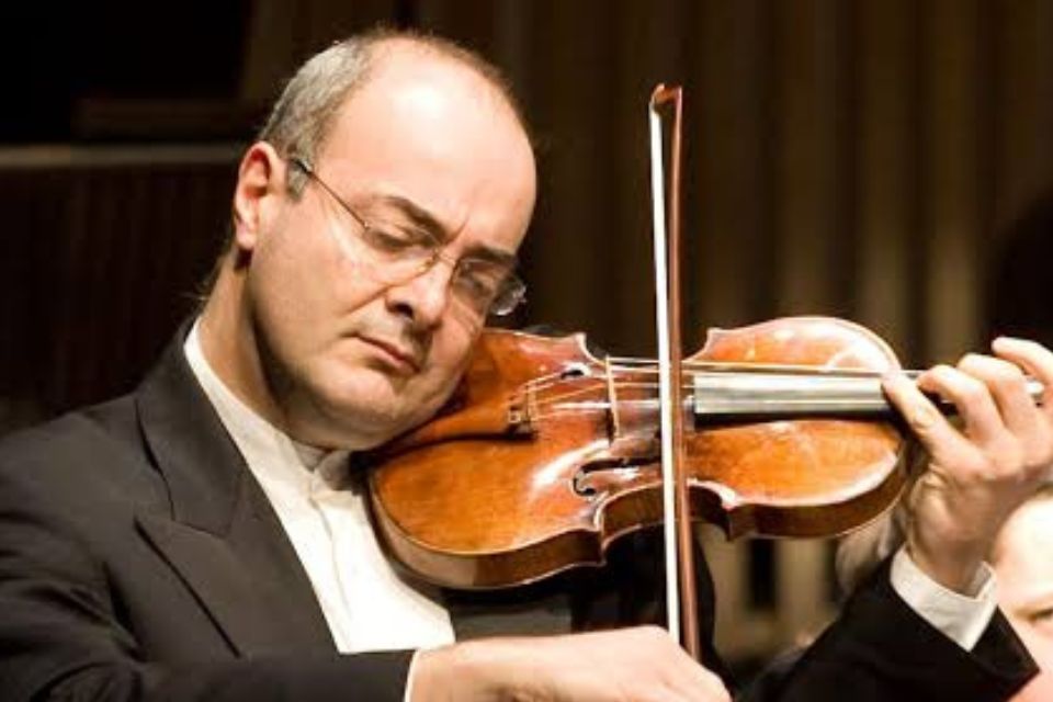 Gordan Nikolić wears glasses and a suit and plays his violin with his eyes closed
