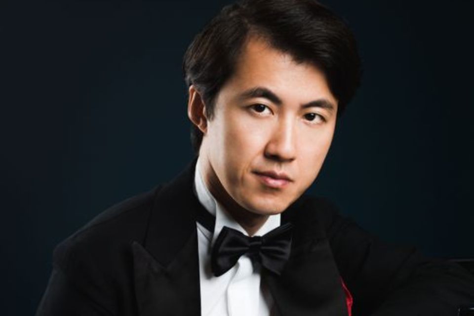 Haiou Zhang wears a tuxedo against a black background, smiling