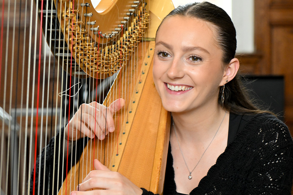 A harpist smiles as she plays her instrument