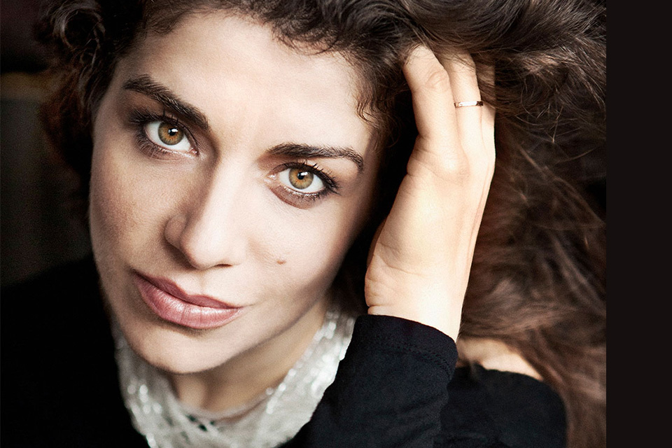 A close up image of Inna Faliks looking to camera with her hand in her hair