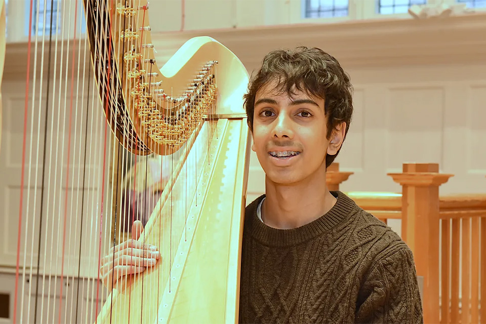 Jamaal Kashim holds his harp and smiles