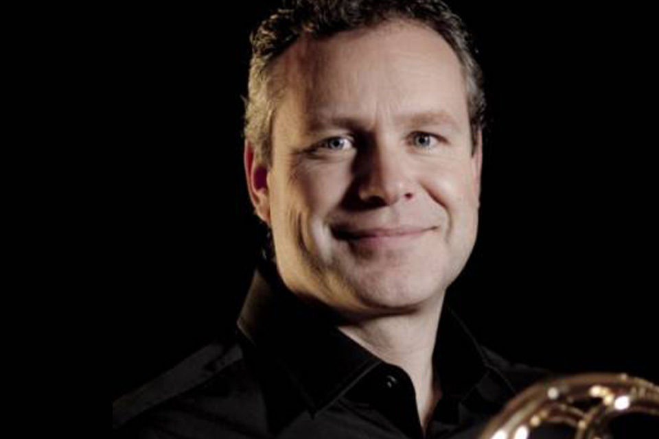 Jasper de Waal wears black and smiles to the camera, against a black background