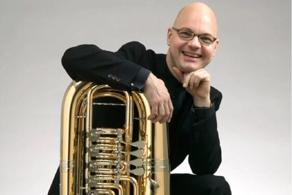 Jens Bjørn-Larsen, wearing black, leans on his tuba and smiles