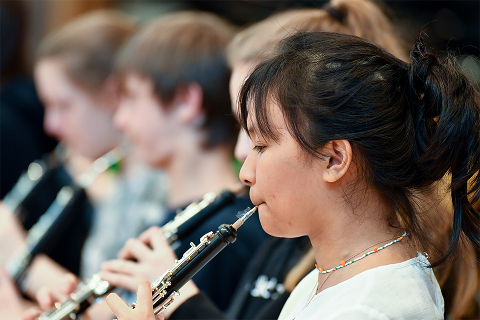 A young girl plays the oboe in an orchestra