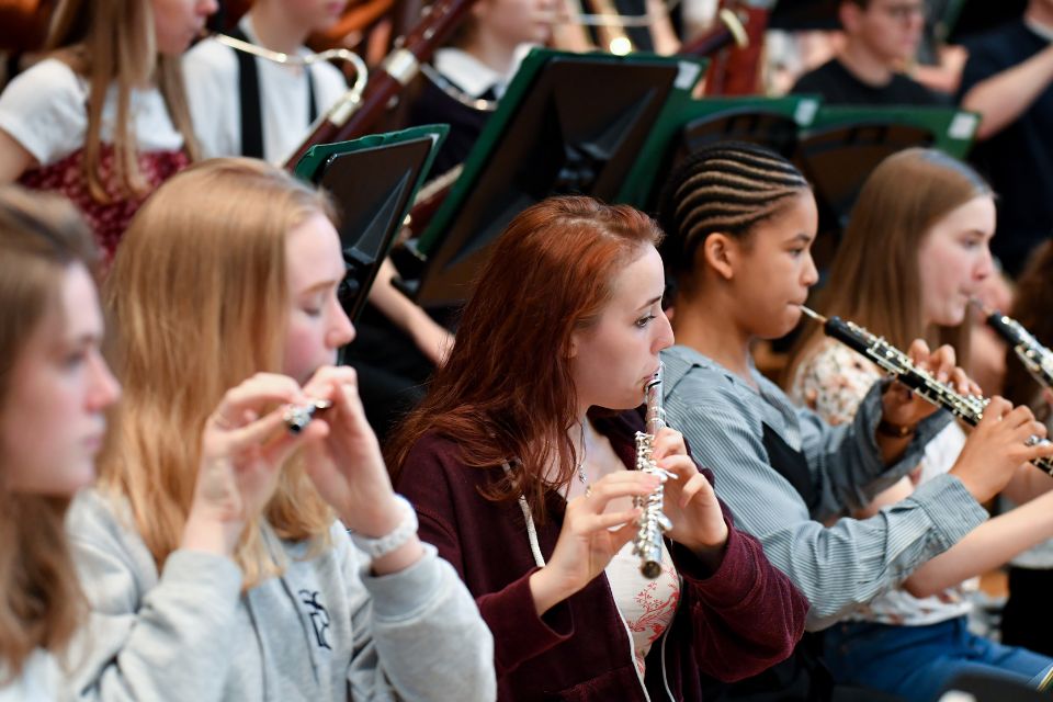 Four girls plays their flutes in an orchestra on stage