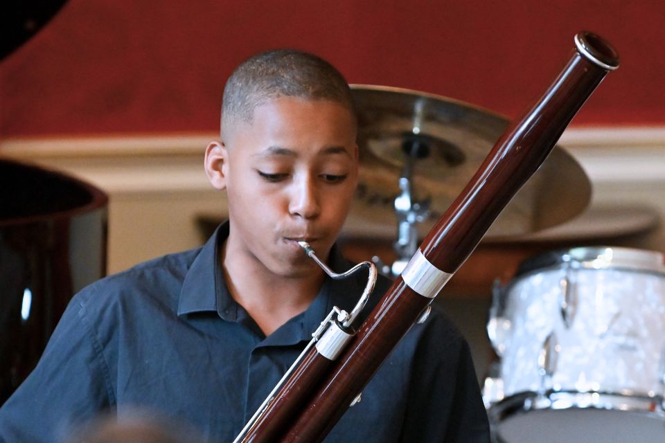 A young boy in a black shirt plays the basson 