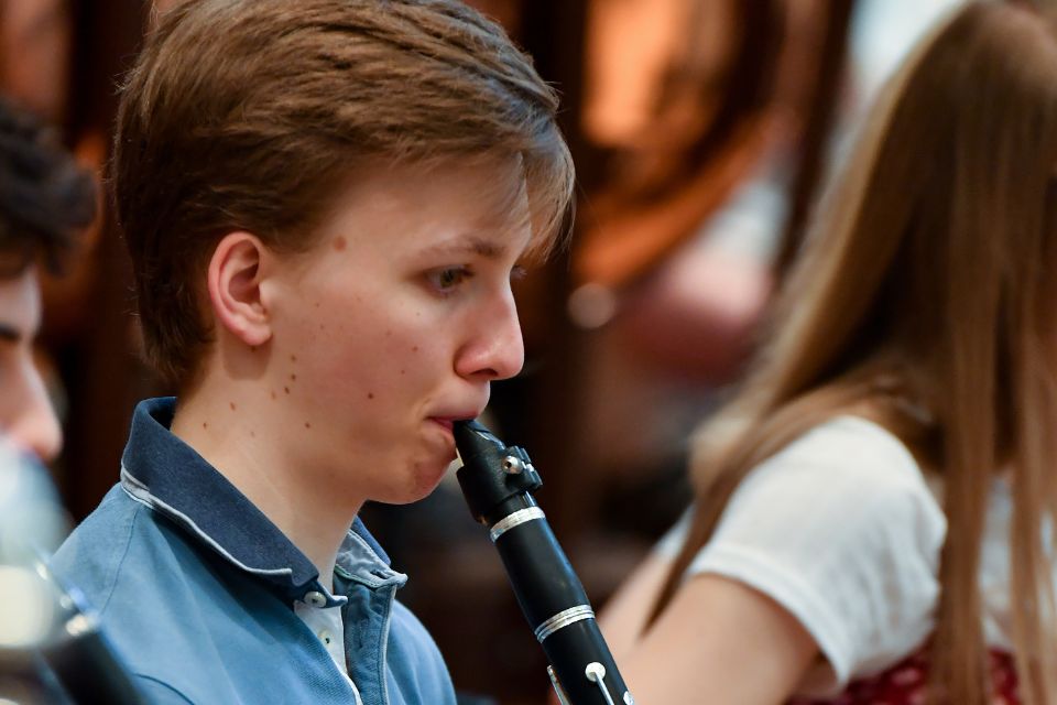 A boy plays his clarinet on stage as part of an orchestra