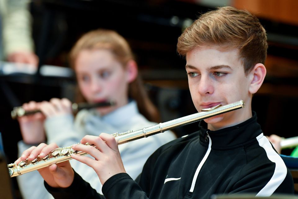 A boy and girl play their flutes on stage