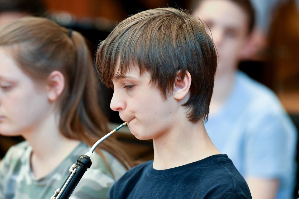 A boy plays the cor anglais on stage as part of an orchestra