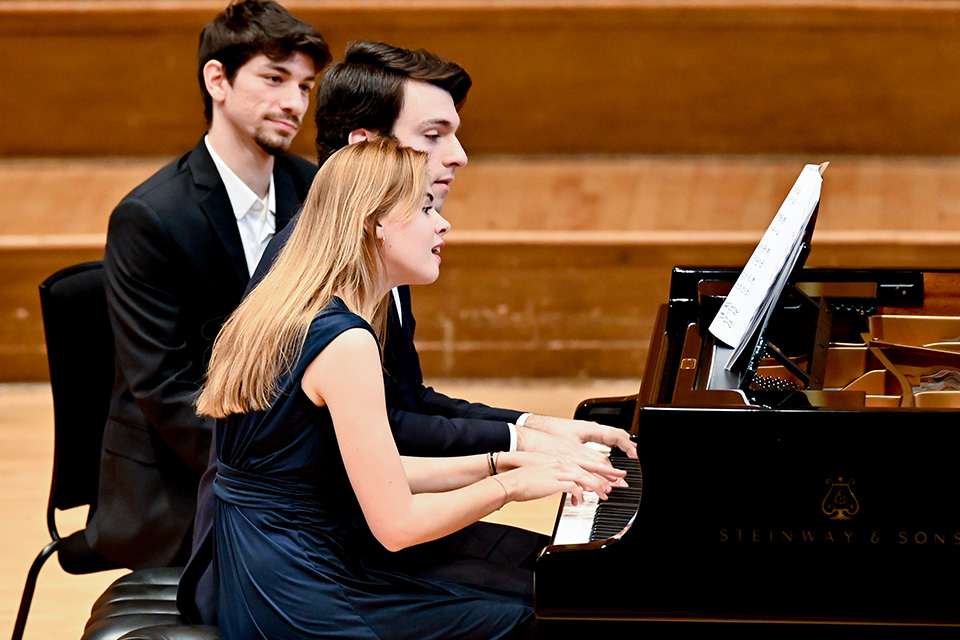 Two pianists perform the piano together on stage