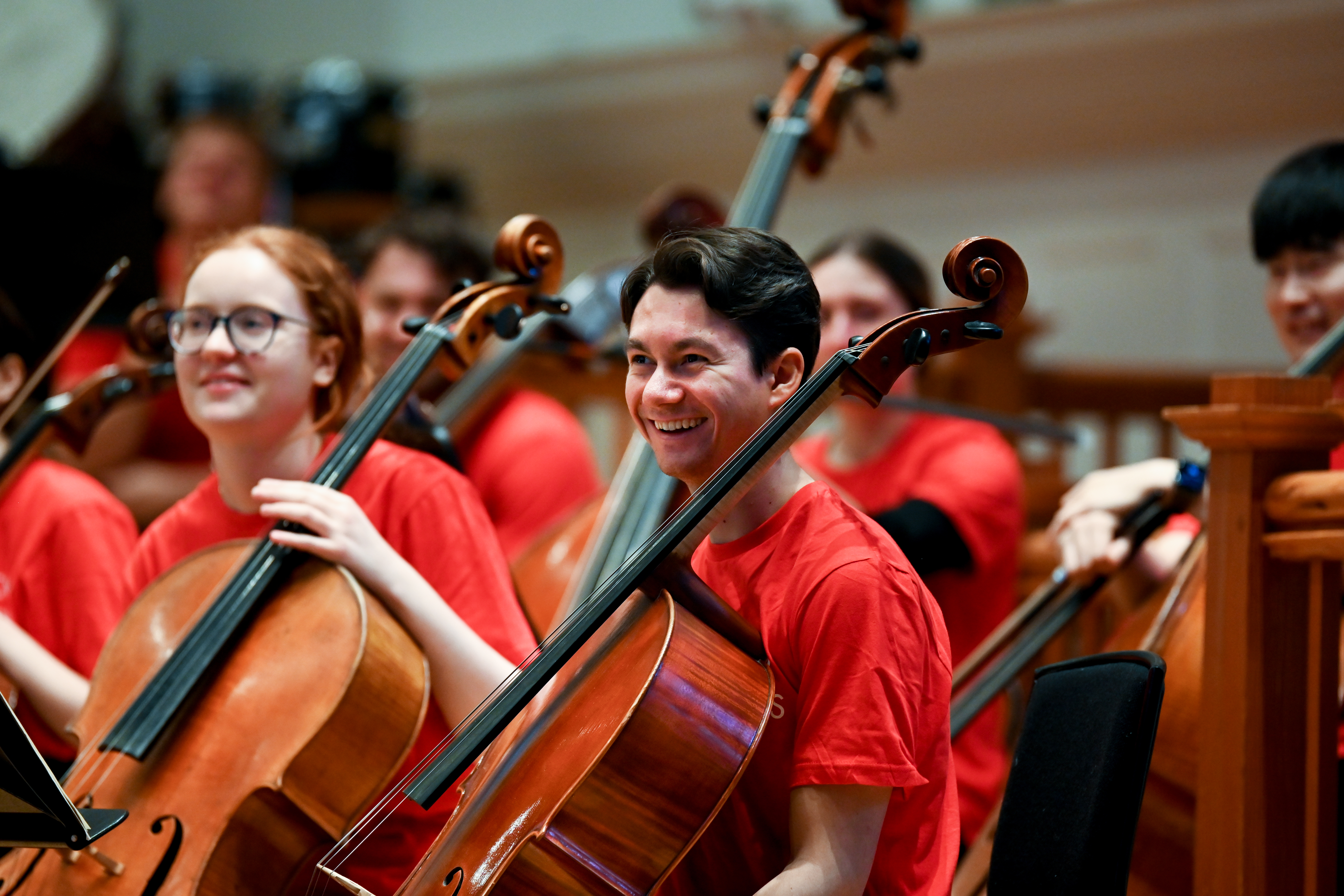 Two cellists wearing red and smiling