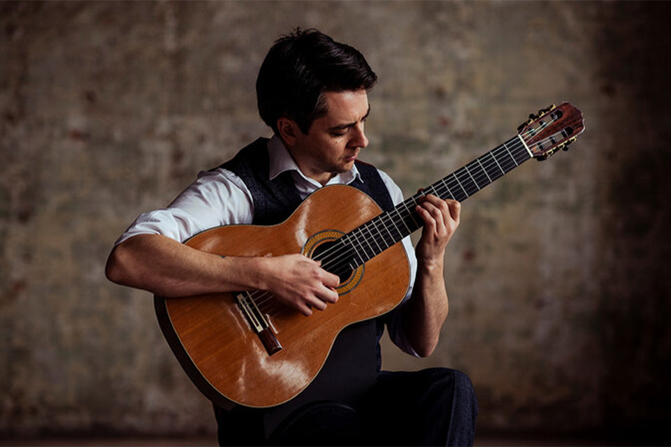 Marcus Noble looks down at his guitar as he plays