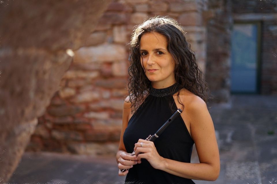 Marta Santamaría Llaval holds her piccolo in a sunny walled garden