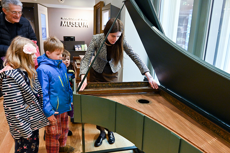 Museum guests smile as they look at an instrument in an exhibition display case