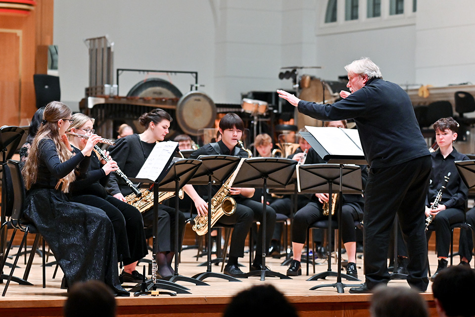 A conductor leads a chamber group animatedly on stage