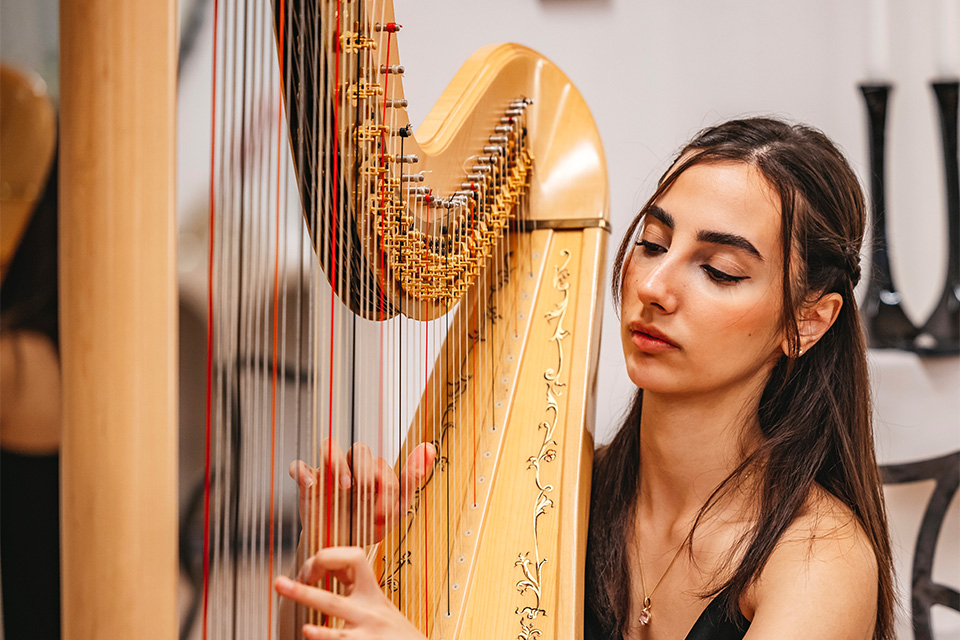 Tannaz Beigijouinani plays the harp, looking down at her fingers