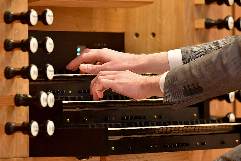 A close up of an organists hands as he plays