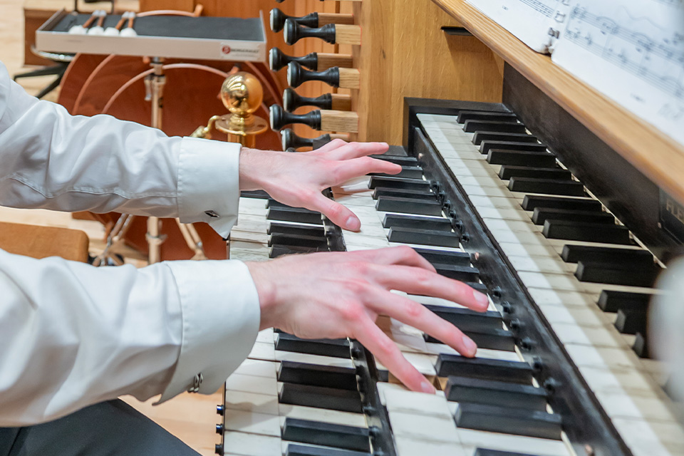 A close up of a performer's hands playing the organ in the Amaryllis Fleming Concert Hall