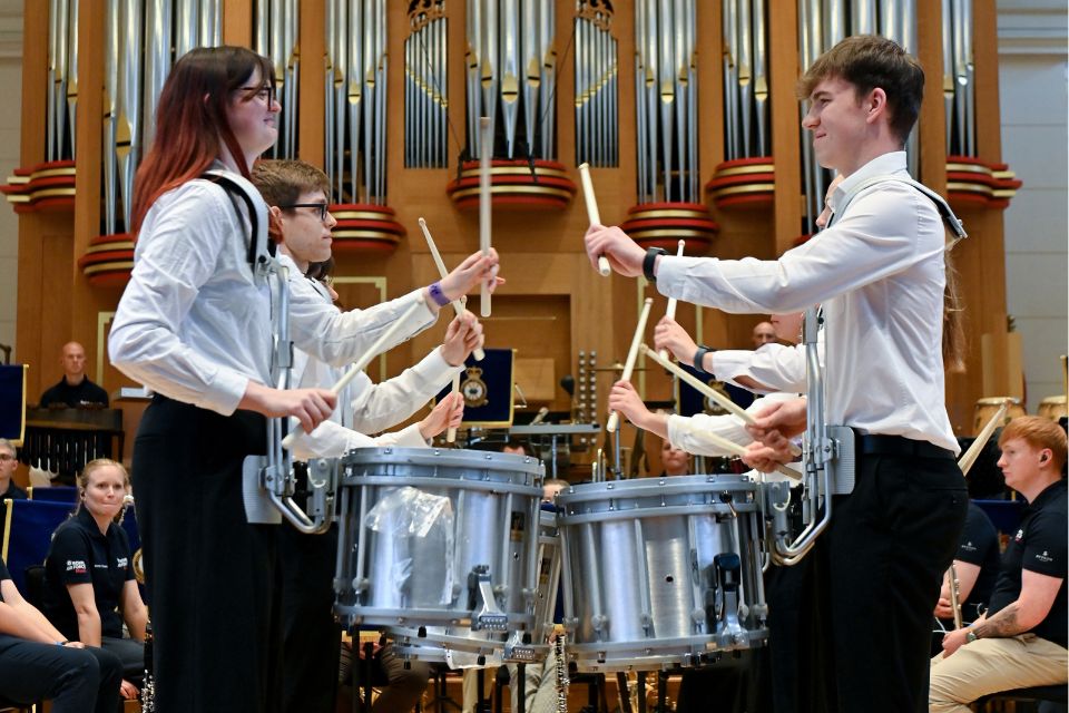 A group of percussionists smile as they perform on stage