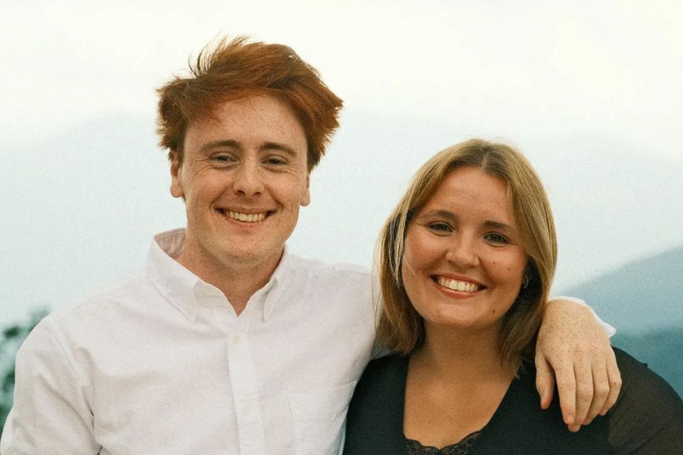 The Chantefable Duo smile with a landscape of mountains behind them