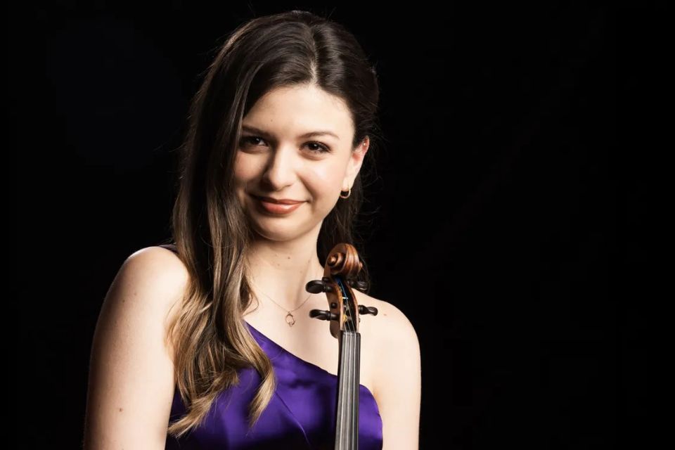 Elif Cansever wears a purple dress and holds her violin