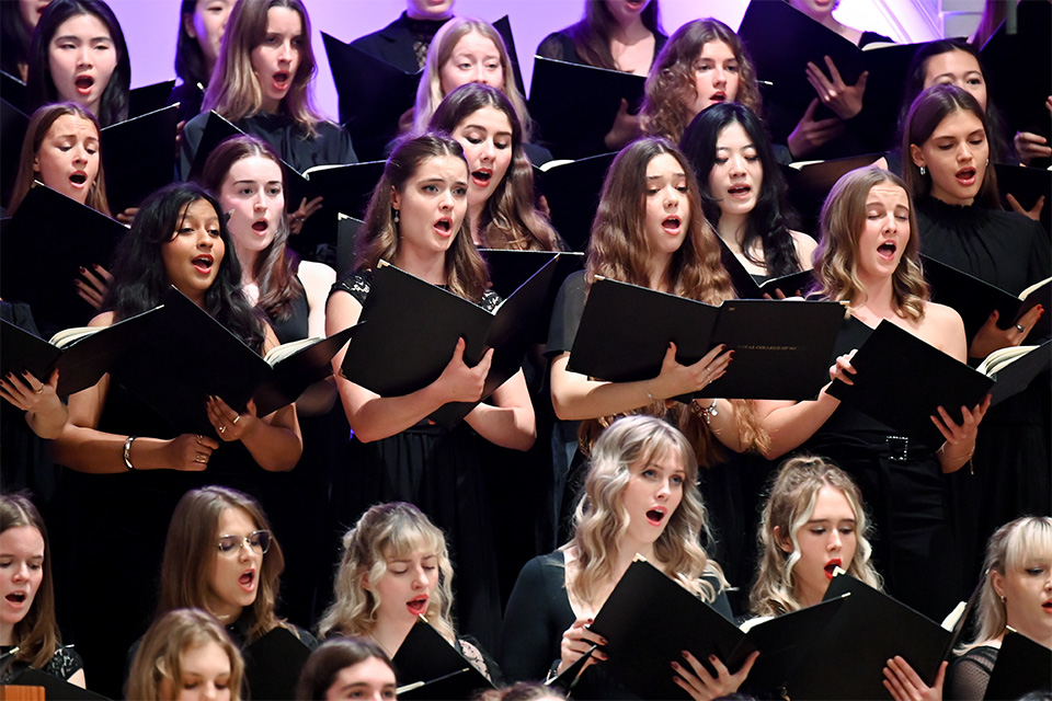 Women sing passionately as part of a large choir
