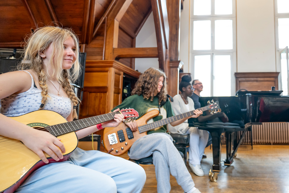 Two girls play guitars and smile