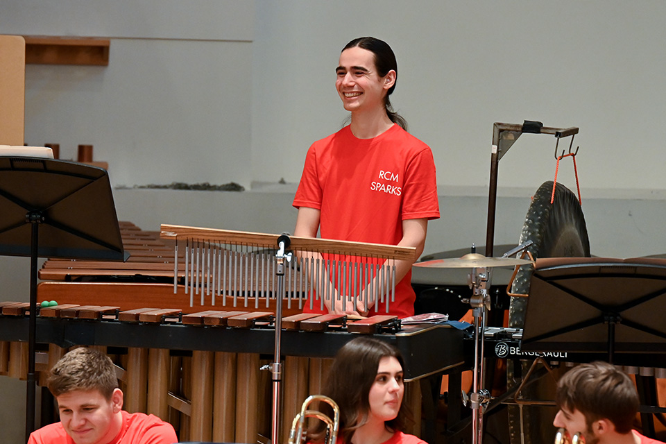 A percussionist in an orchestra smiles during a performance