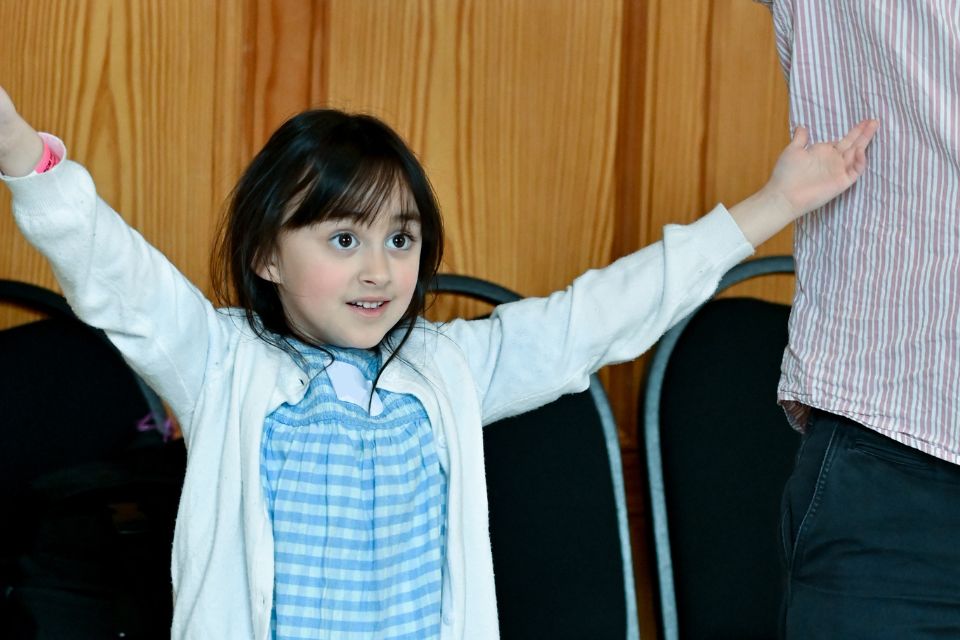 A young girl smiles with her hands in the air