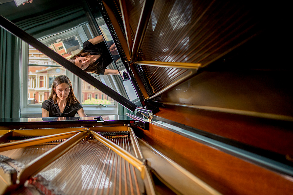 A woman performs the piano in an image taken through its open hood