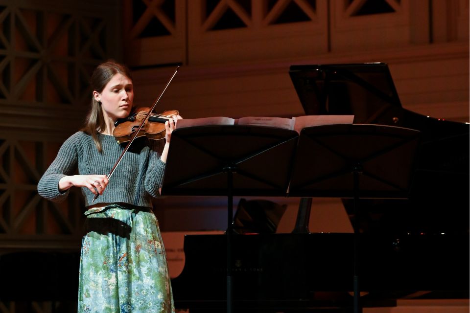 A young woman plays the violin on stage