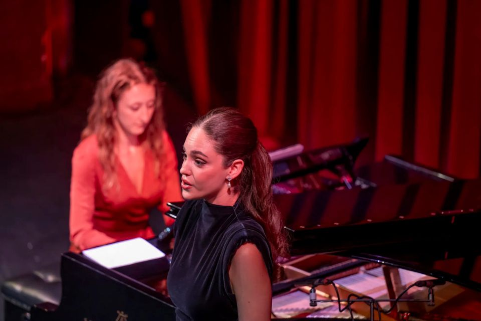 A singer performs on stage in front of a red curtain