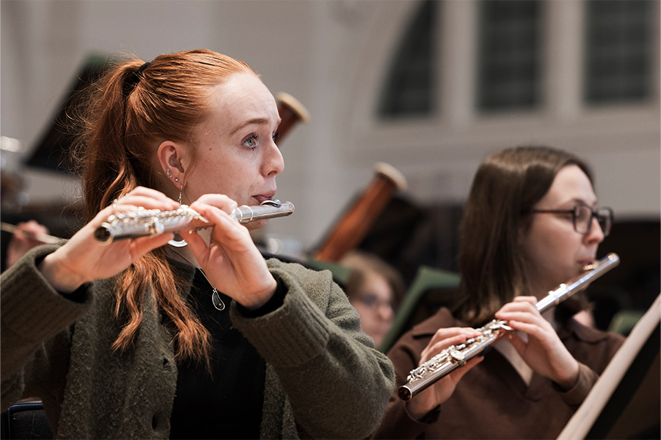 Two young women play the flute on stage