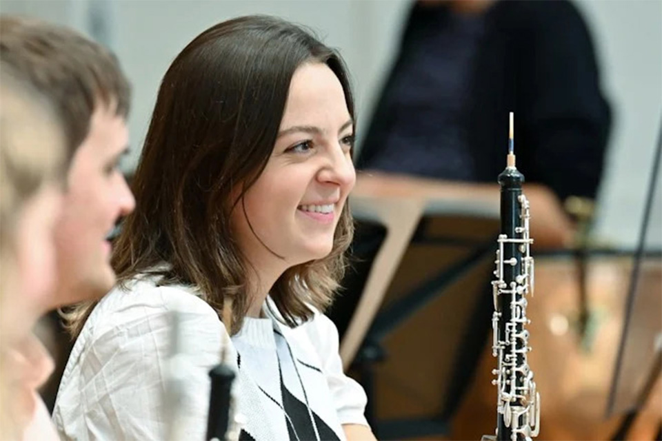 A girl holding an oboe smiling