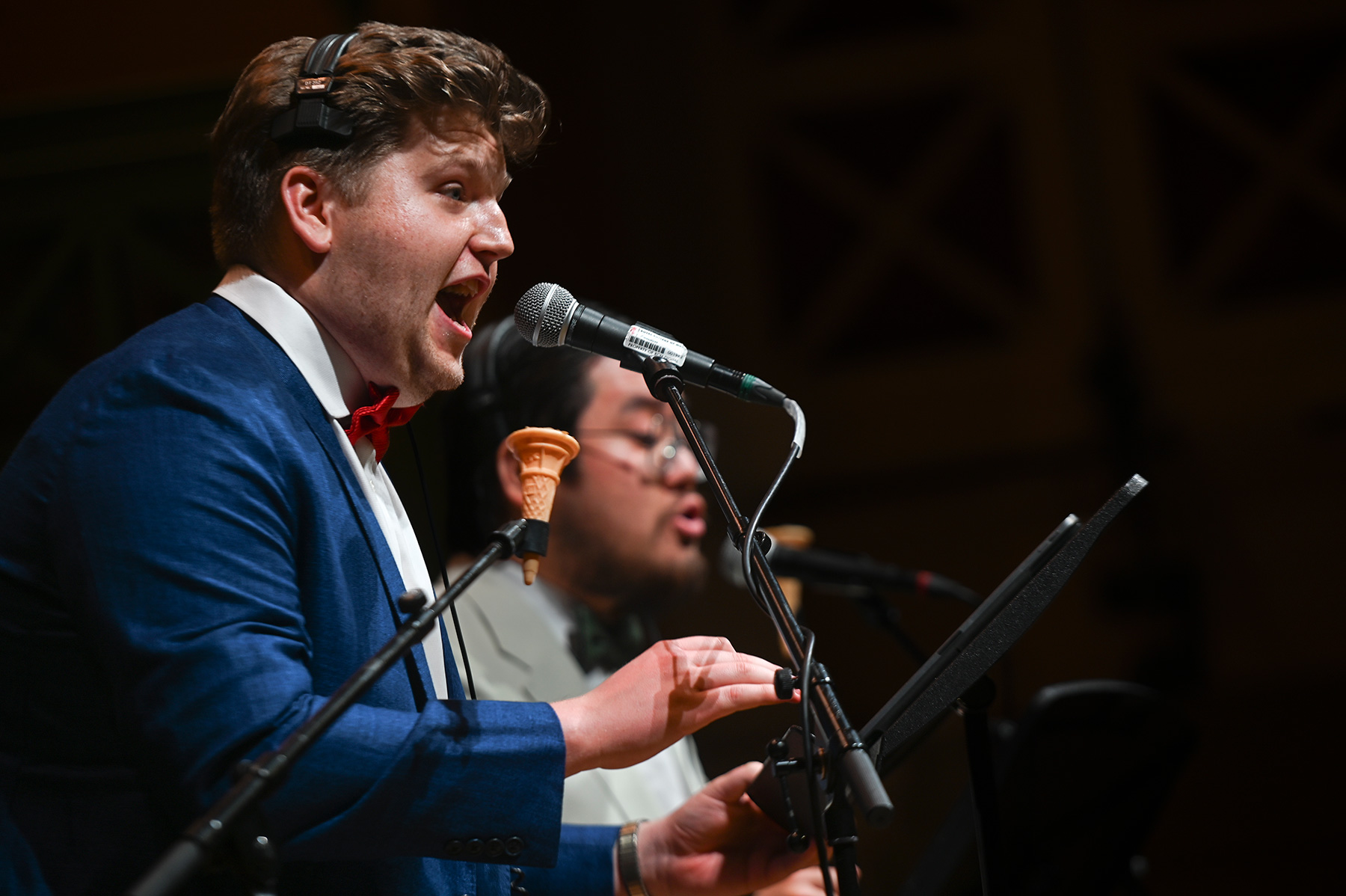 Two students singing on stage with a microphone in front of them.