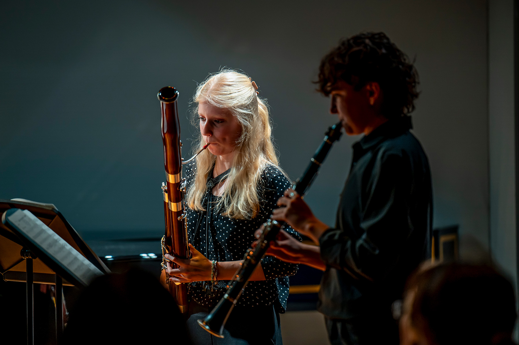 Two students playing the clarinet and bassoon in a quartet performance on a stage.